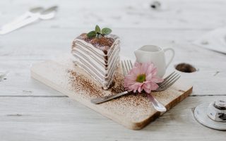 delicious piece of cake and flower on wooden table